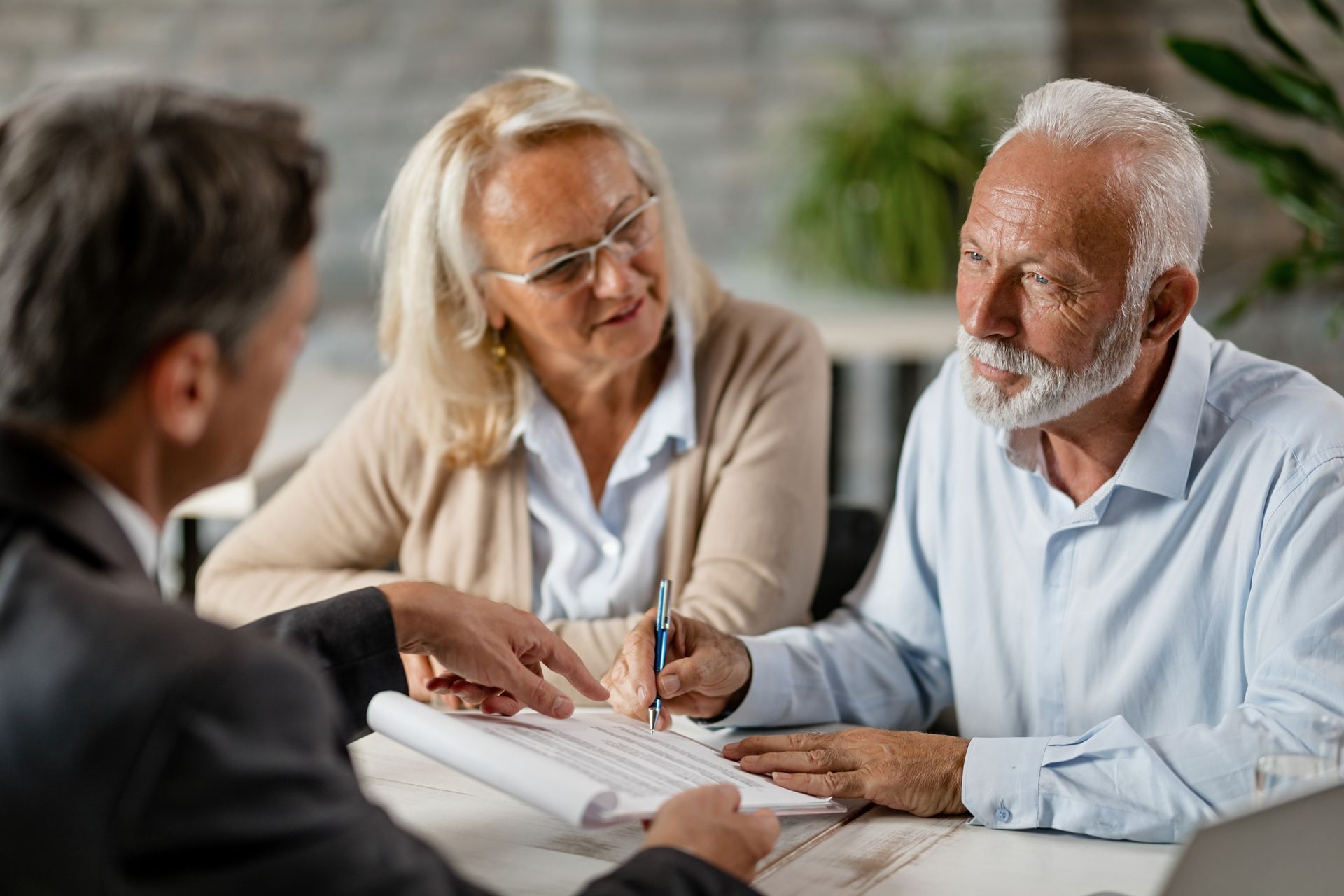 An elderly couple is sitting at a table talking to a man.