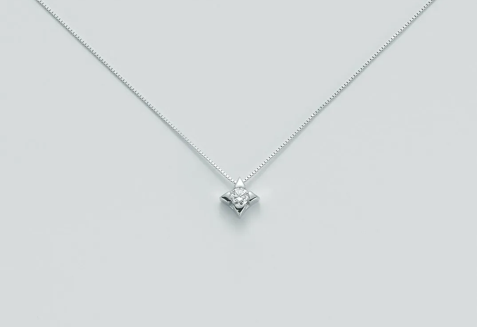 Delicata collana in argento con un piccolo ciondolo di diamanti su sfondo grigio chiaro.