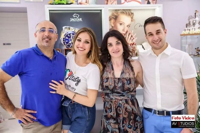 Primo piano di una donna che indossa orecchini a cerchio d'oro e una maglietta gialla, mentre si tocca il mento con un anello gioiello.