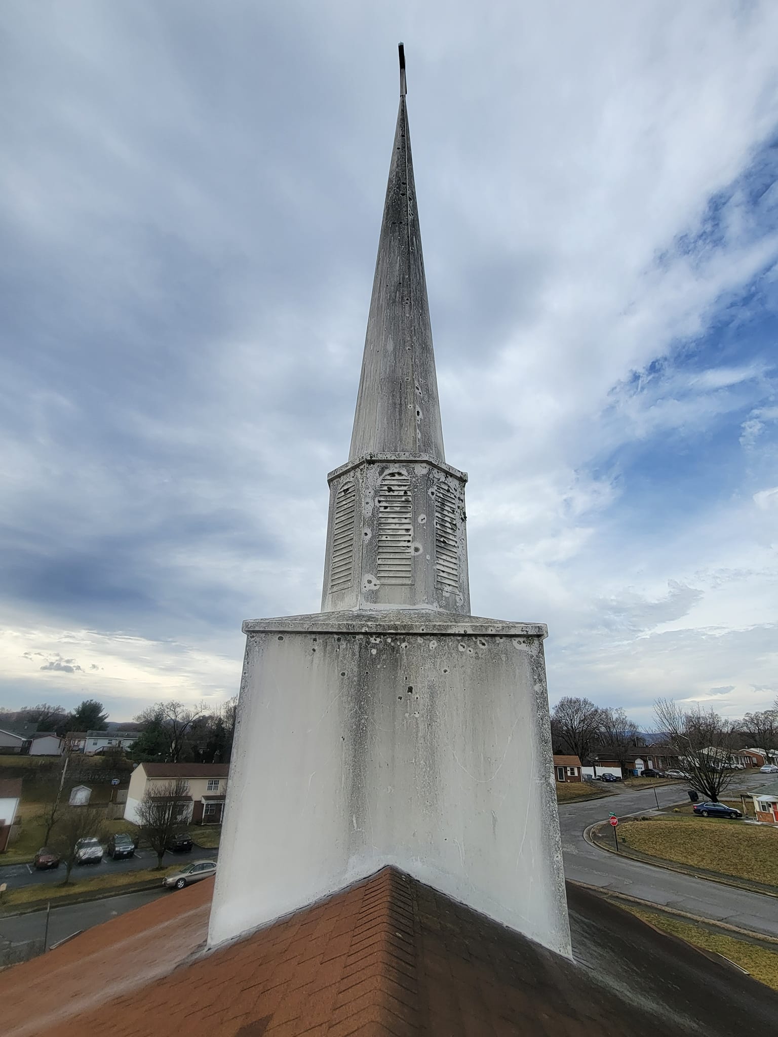 White church steeple against cloudy sky.