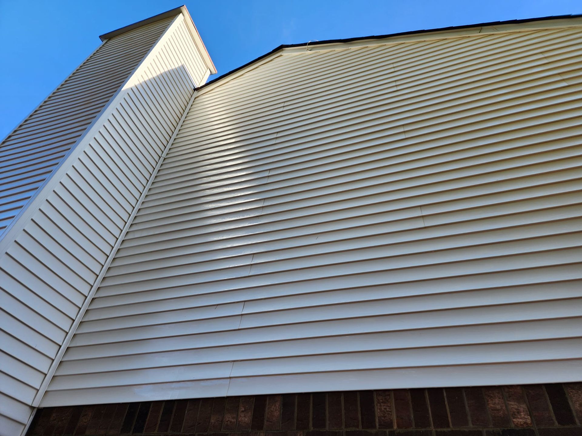 White vinyl siding and chimney on a building against a bright blue sky.