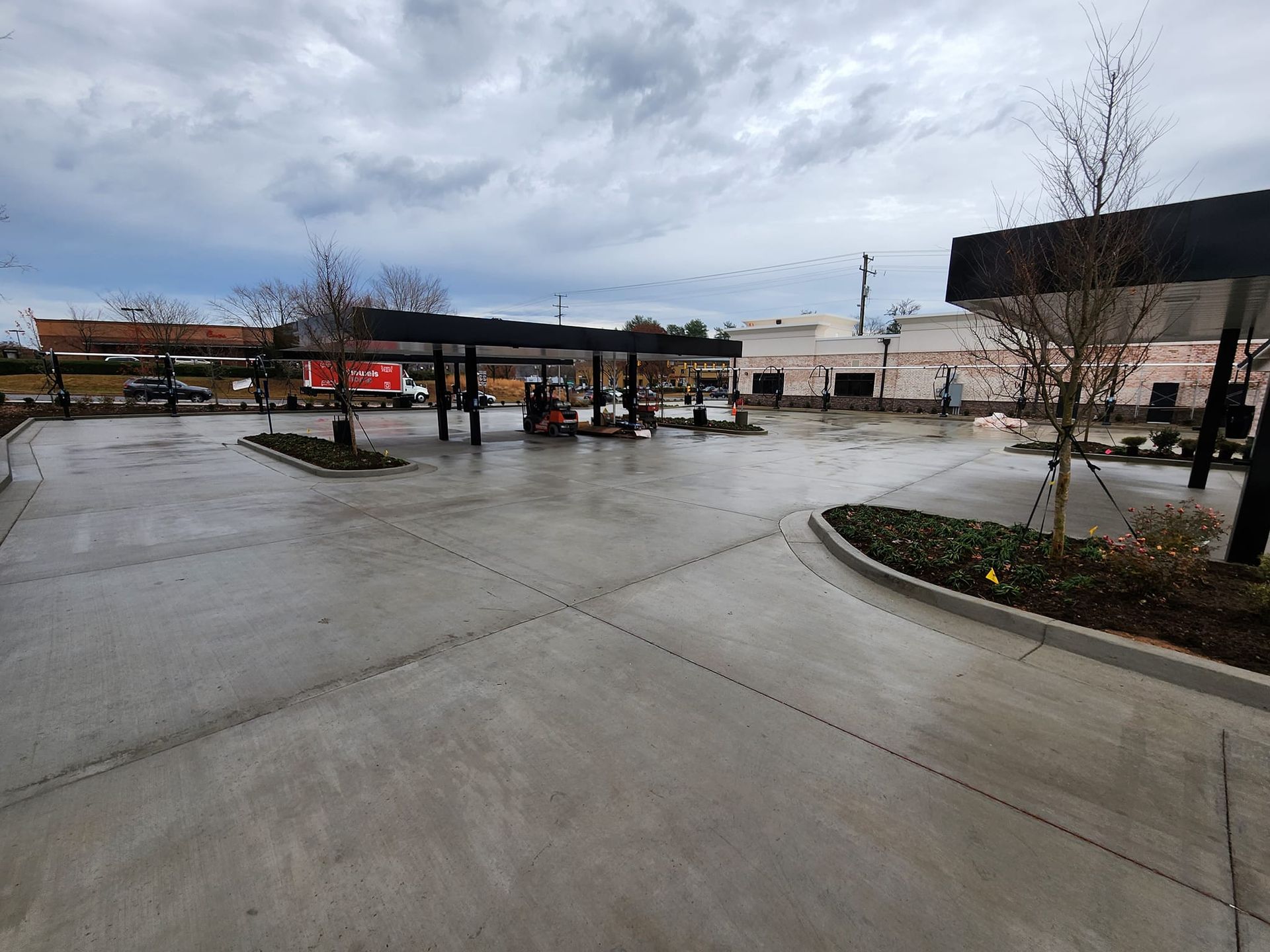 Gas station with canopy, concrete lot, overcast sky.
