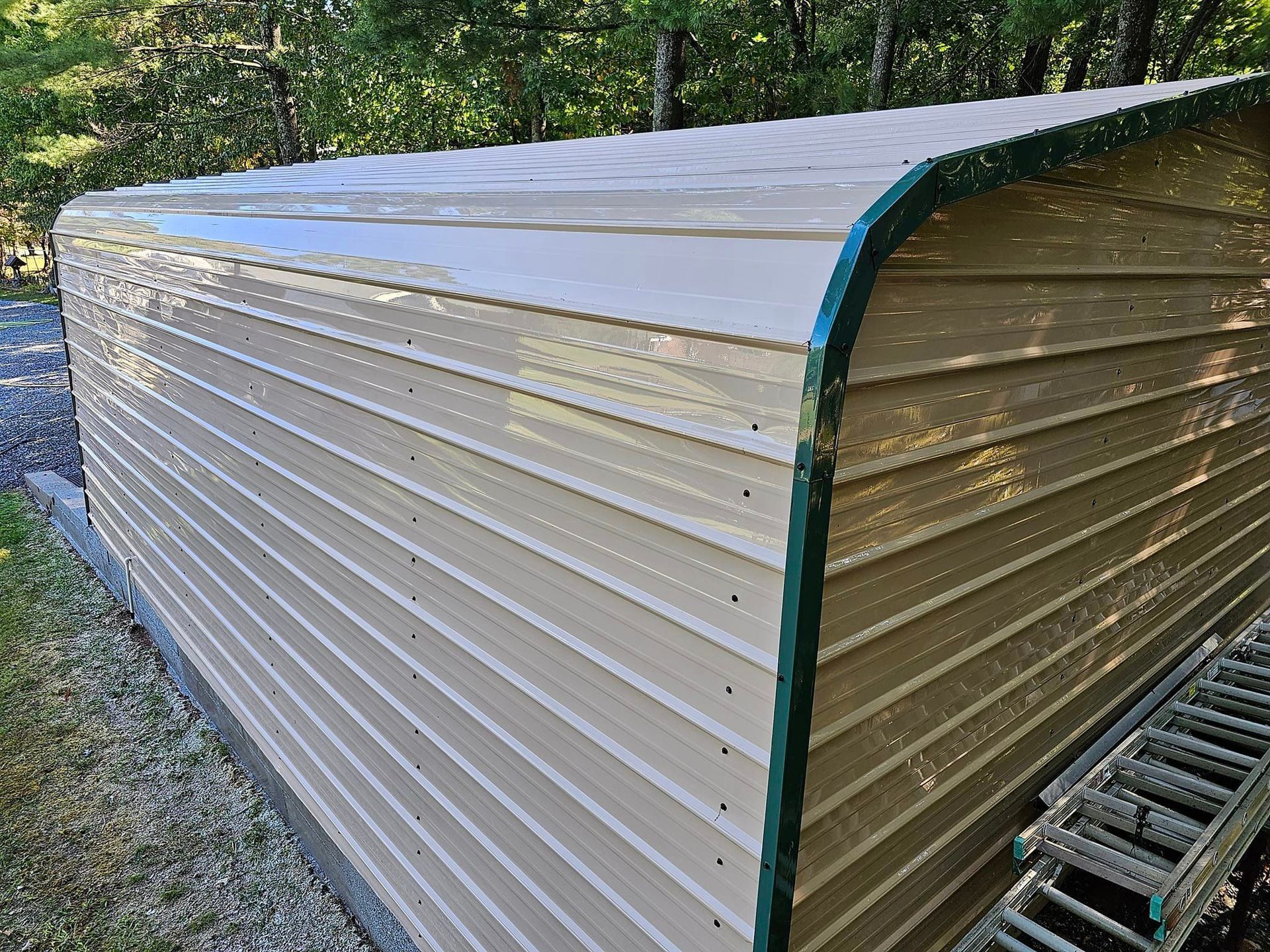 Tan metal storage shed with green trim, outdoors.