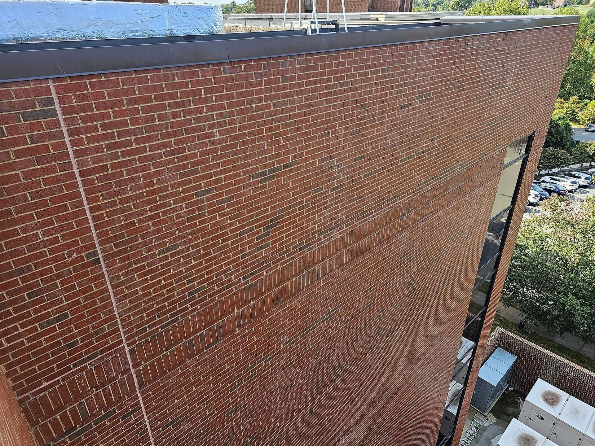 Red brick building exterior with a dark brown roof and window.