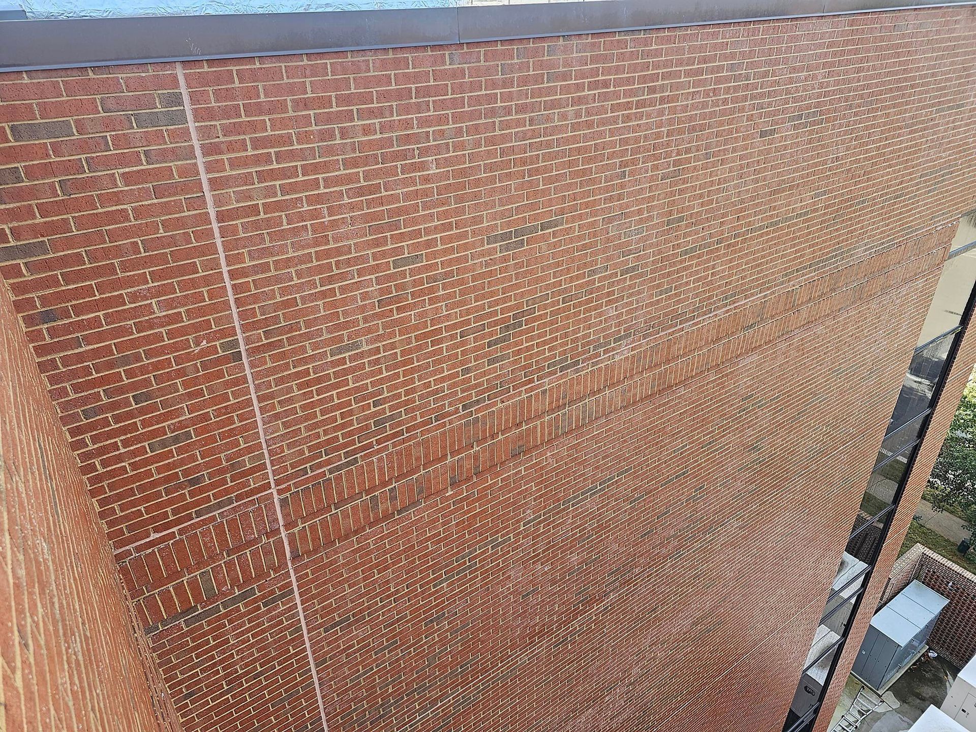 Brick building exterior. Red brick wall. Light-colored mortar. A rope is running vertically.