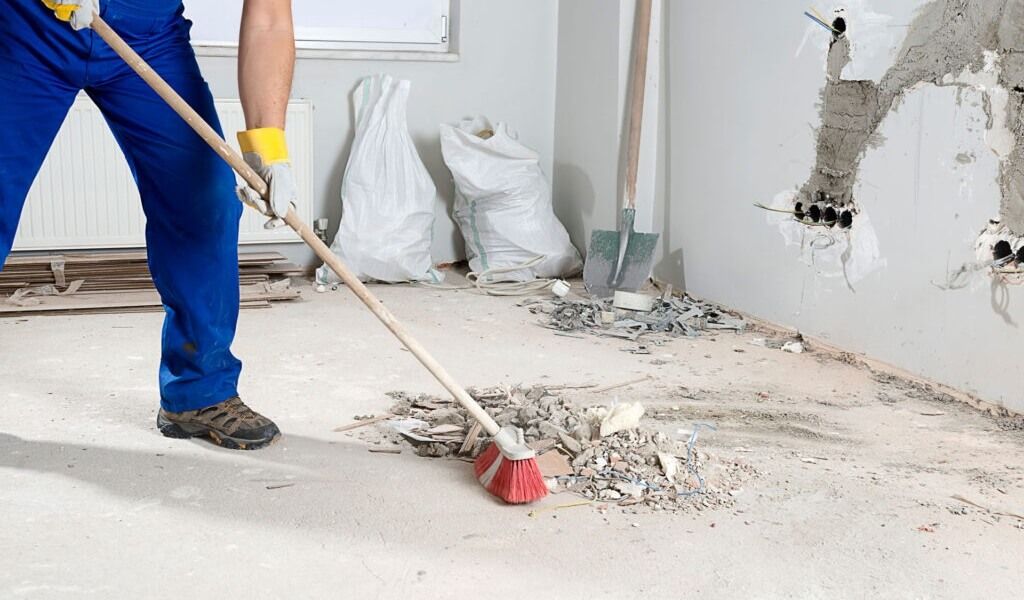 Construction worker sweeping debris from floor.
