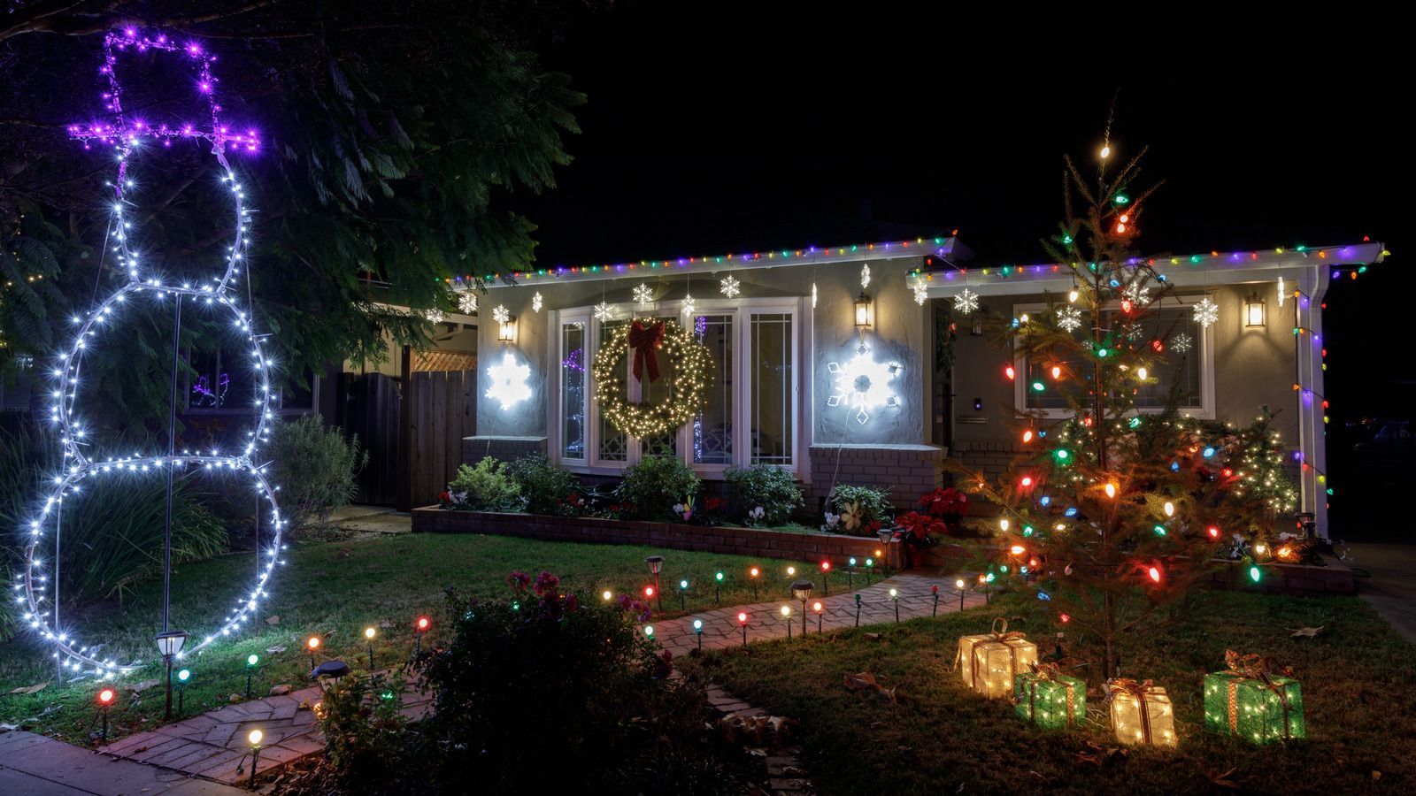 House decorated for Christmas with snowman, tree, and lights.