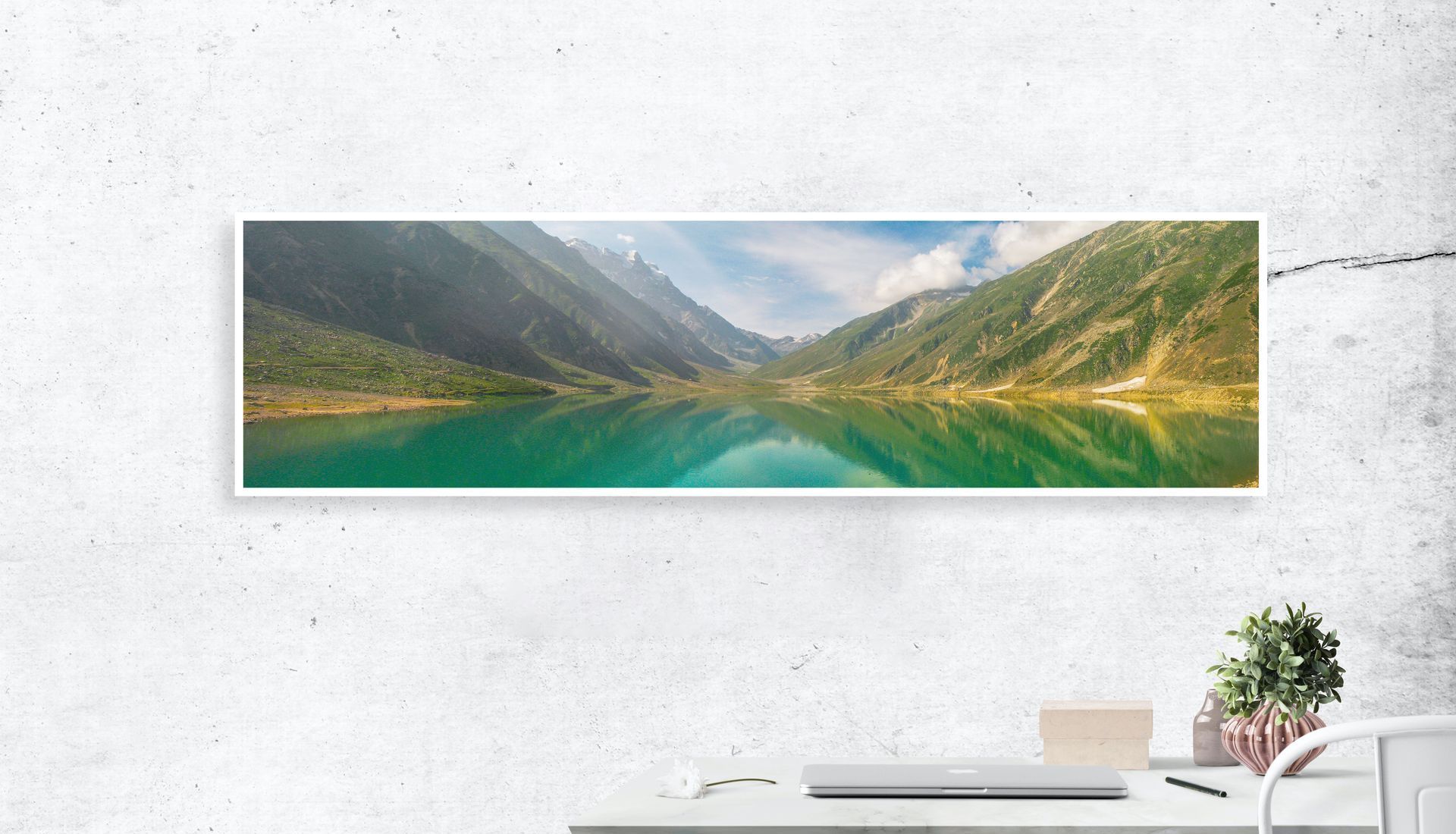 Panoramic print of a lake surrounded by mountains hanging on the wall.
