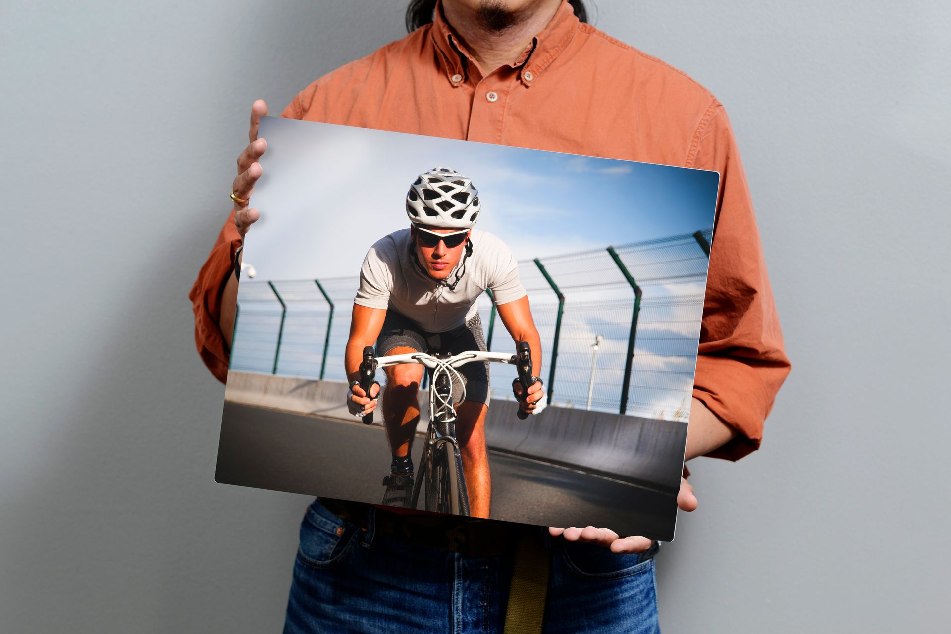 Man holding aluminum print of person on bike