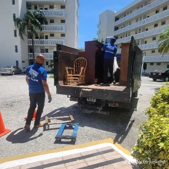 Movers loading furniture onto a truck in a parking lot. Two workers lift a cabinet.