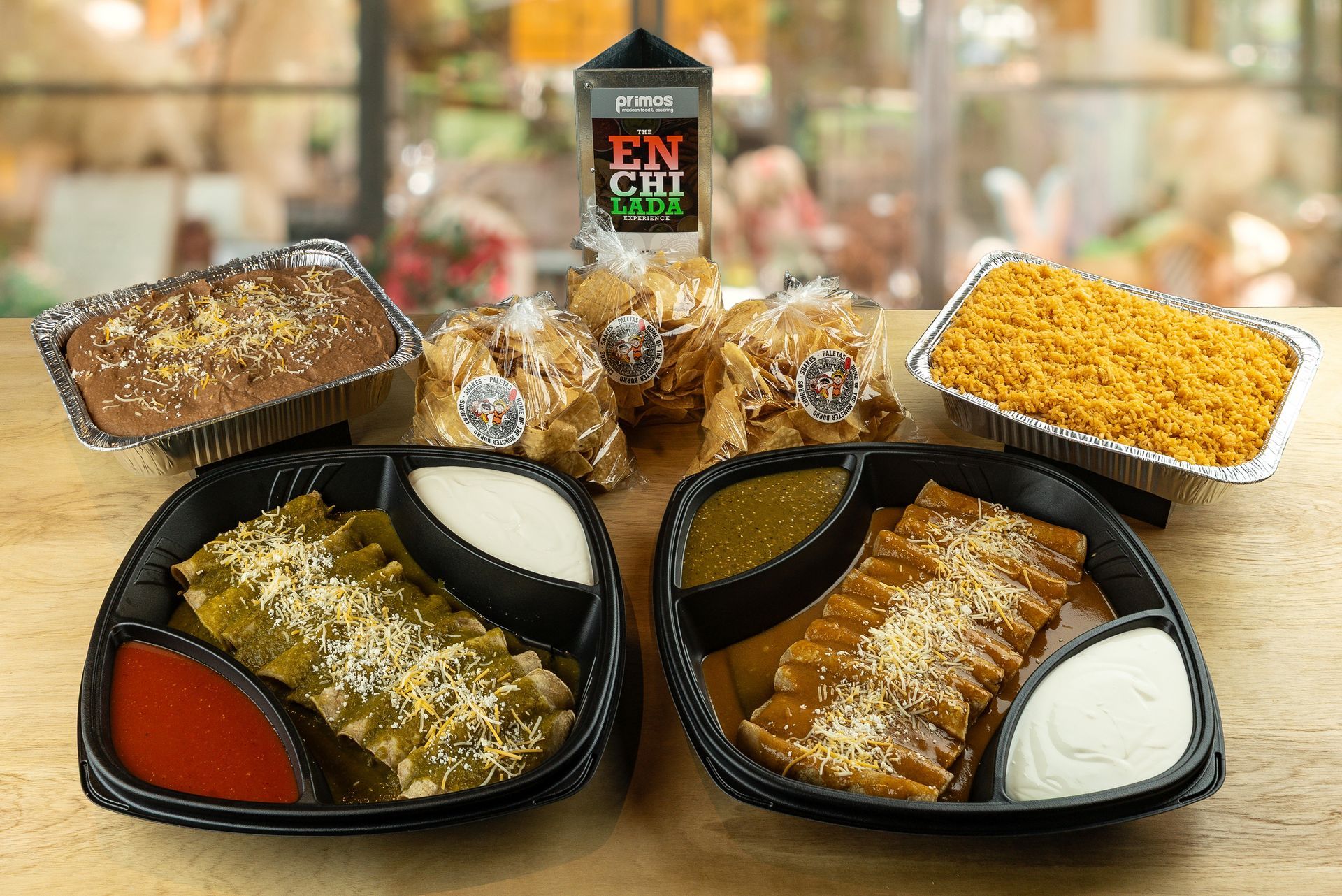 Assorted pastries in black trays on a wooden table, with red, white, and yellow fillings in a café setting