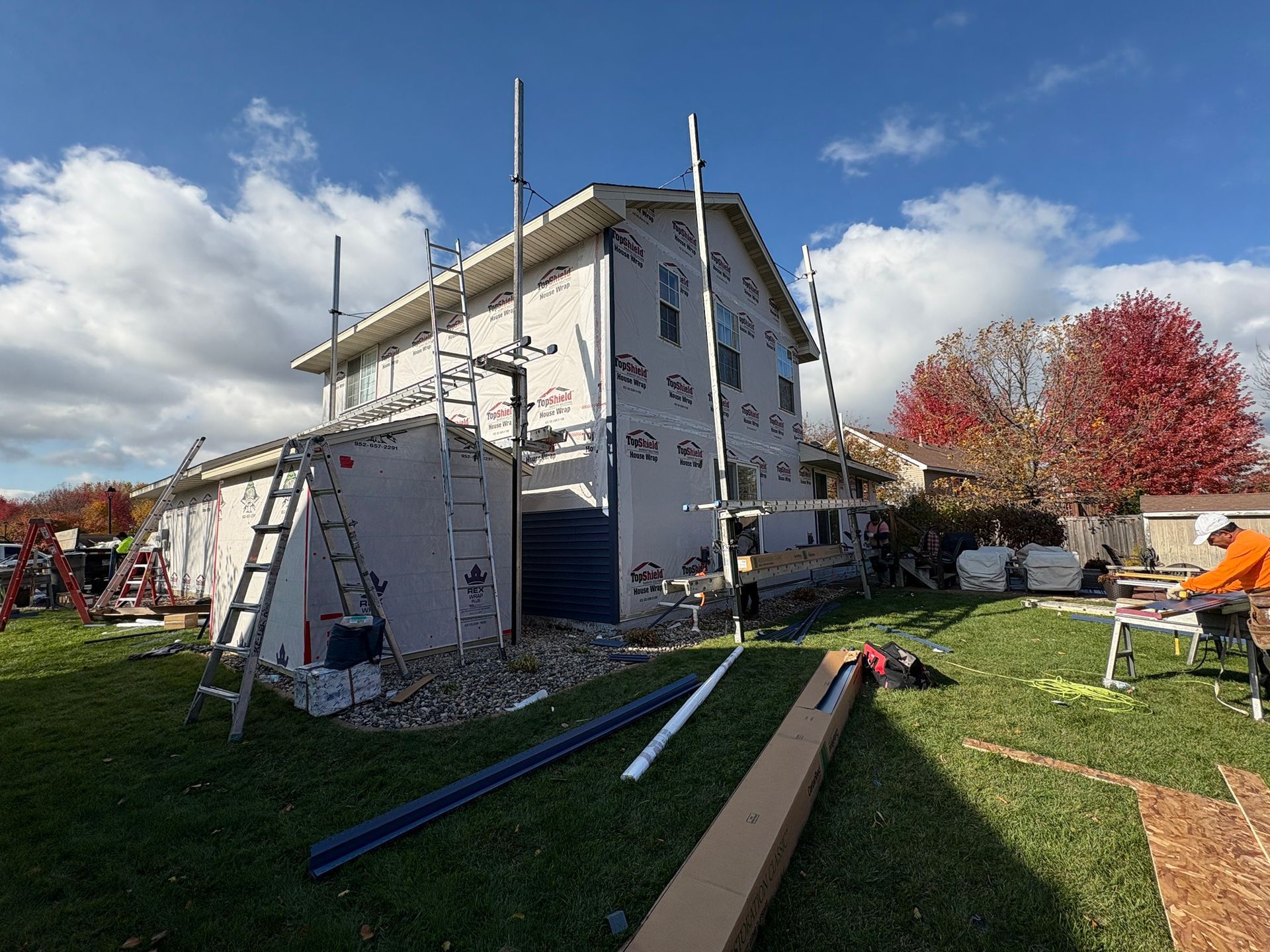 House under construction with scaffolding, tools, and a pile of debris in the yard under a blue sky