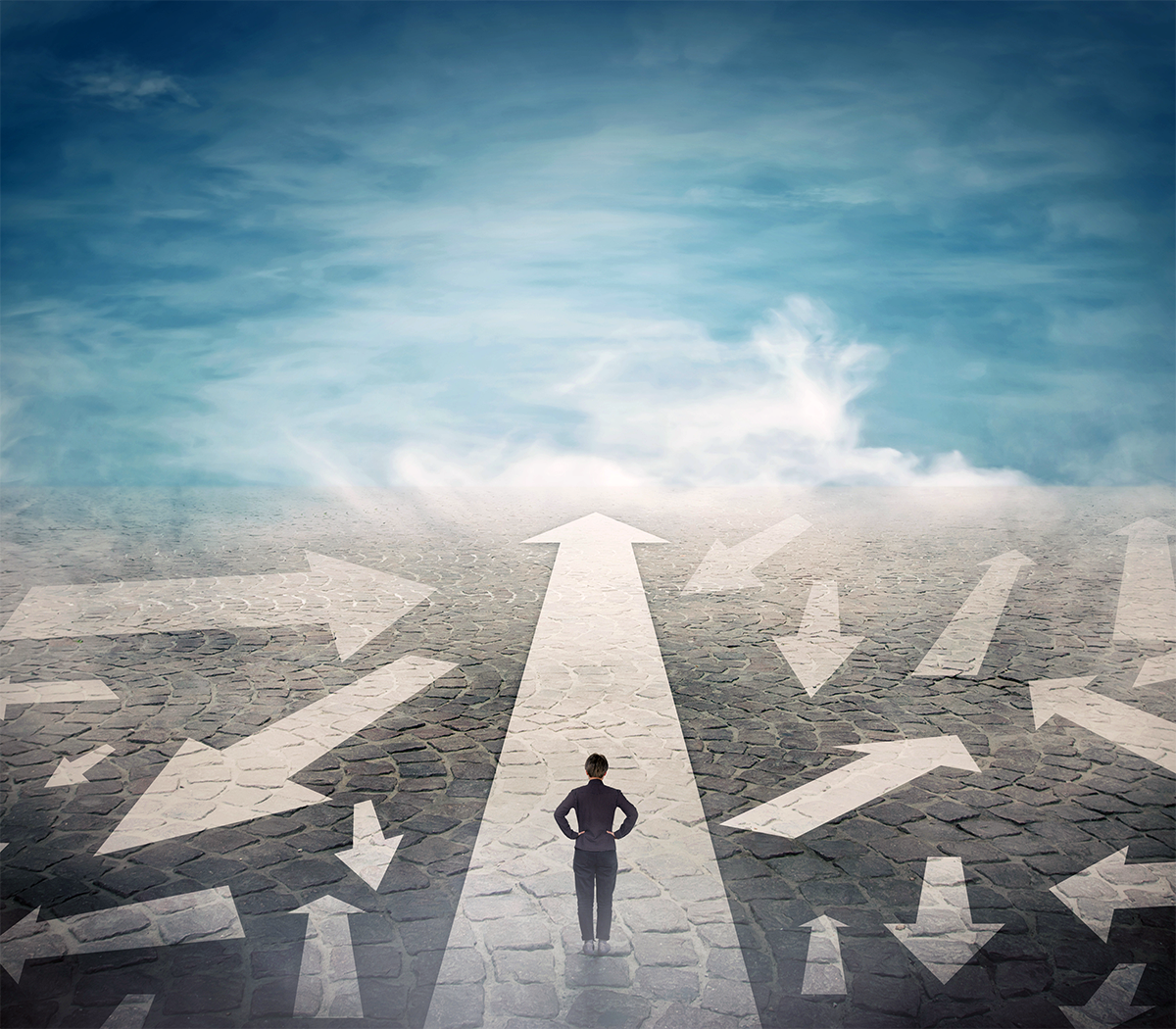 A man is standing in the middle of a road with arrows pointing in different directions.