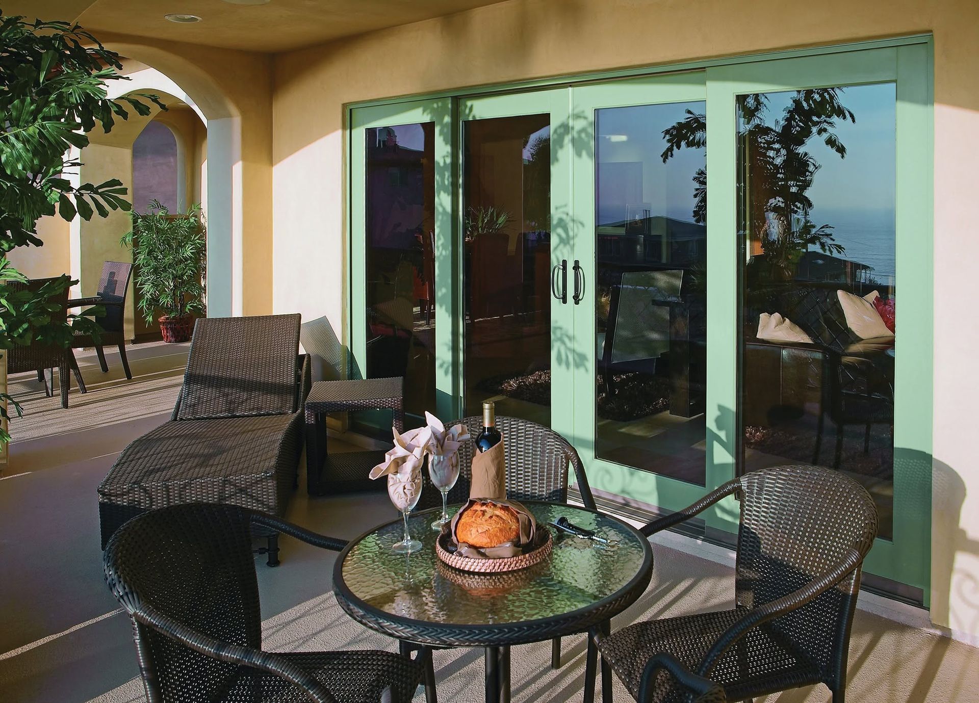 Patio with wicker chairs, glass table, and sliding glass doors under a covered terrace