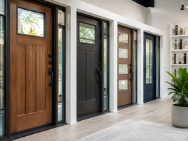 Modern showroom with several front doors in wood, black, and gray along a white wall, plus a potted plant.