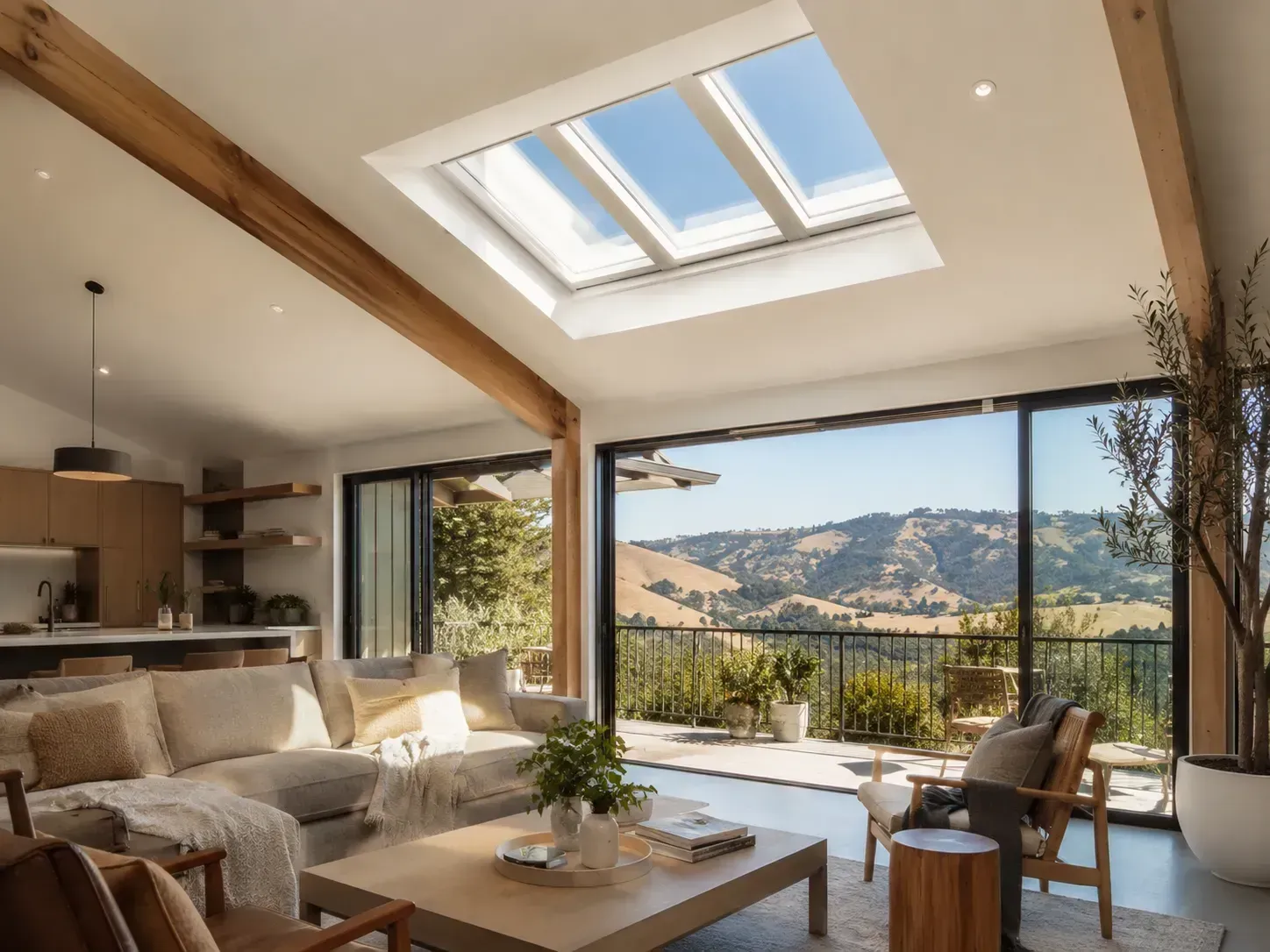 Modern living room with skylight, open terrace, and mountain view beyond glass doors