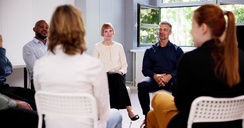 A group of people are sitting in a circle talking to each other.