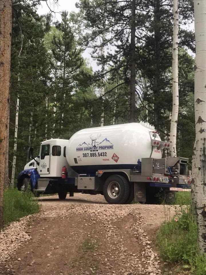White utility truck on a gravel forest road among tall trees and green bushes
