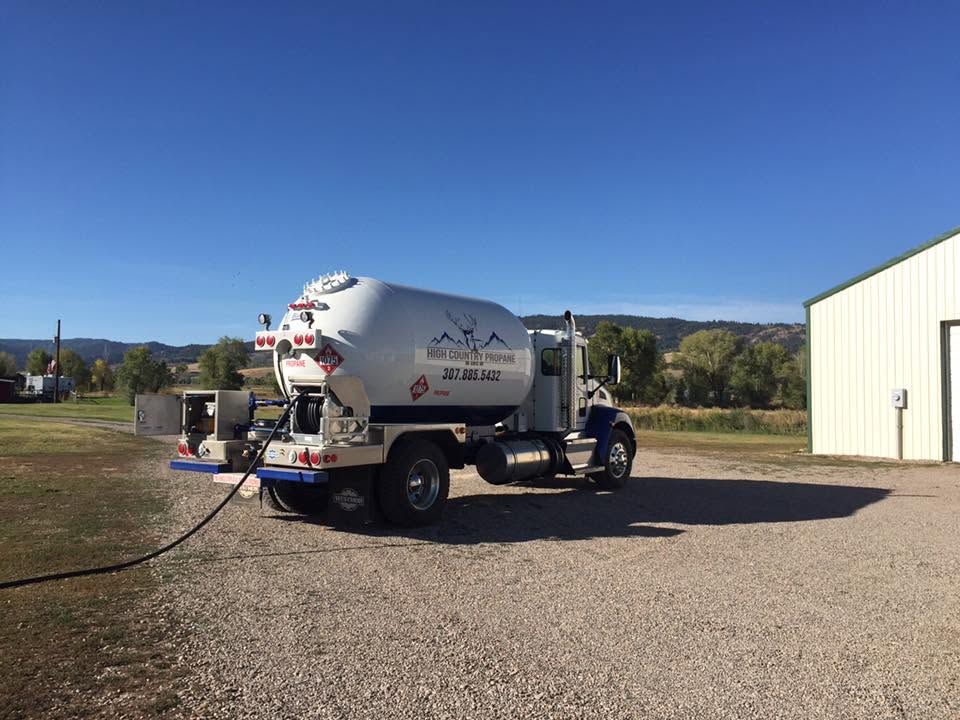 White cement mixer truck parked on gravel beside a metal building under a clear blue sky.