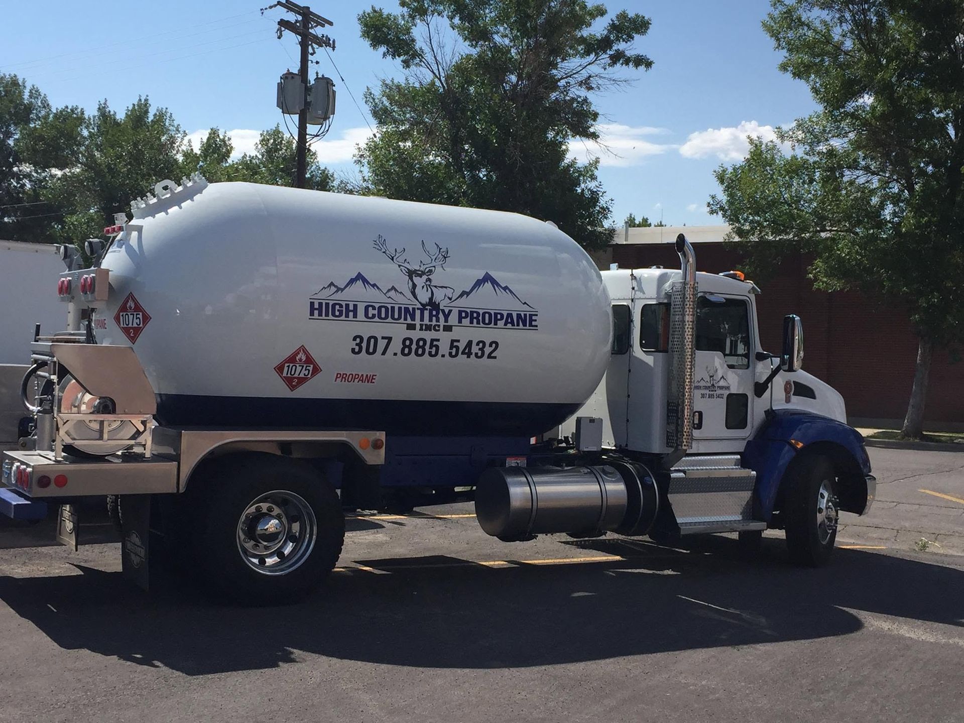 White septic truck parked outdoors under a blue sky, with company logo and phone number on the tank.