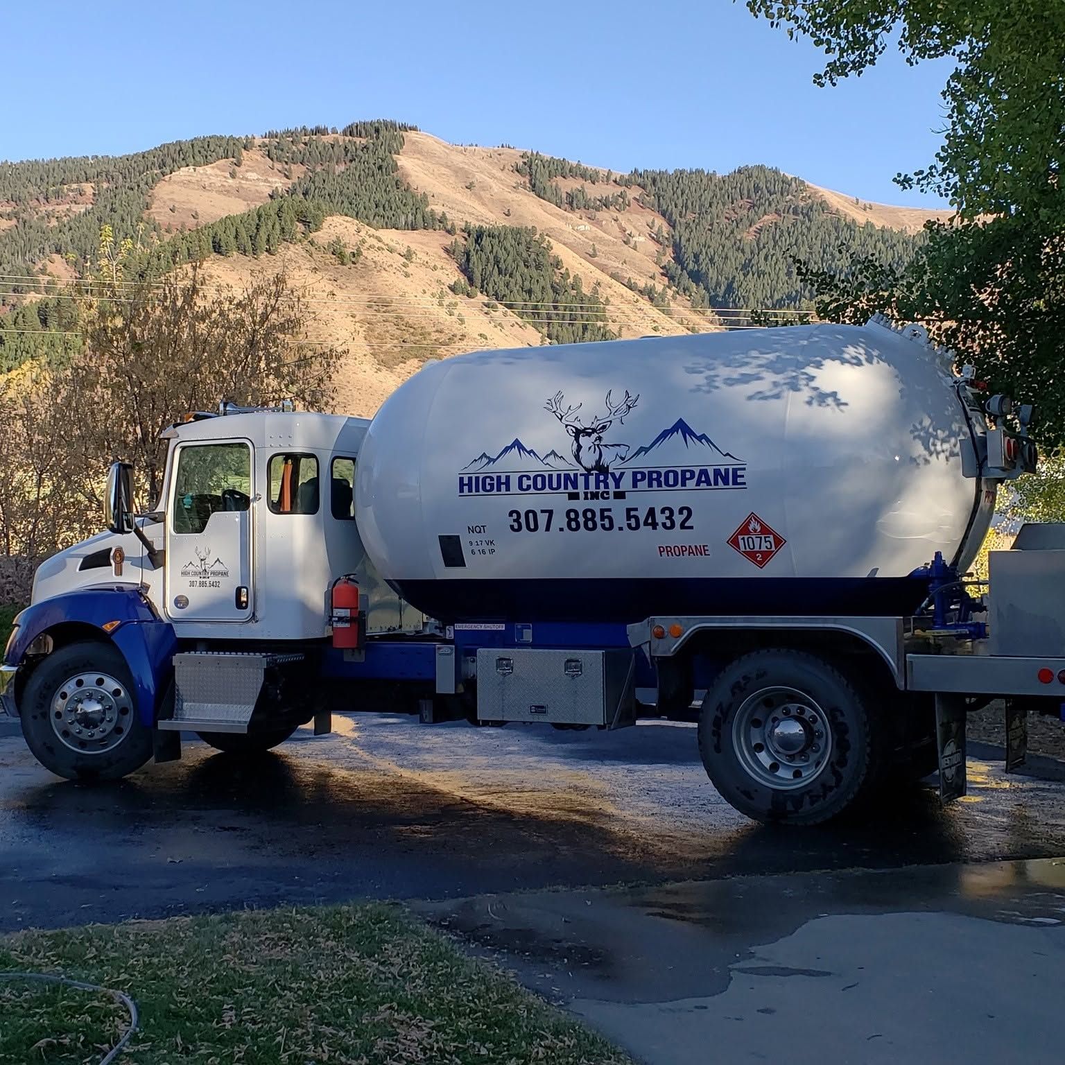 White propane delivery truck parked outdoors with mountains in the background
