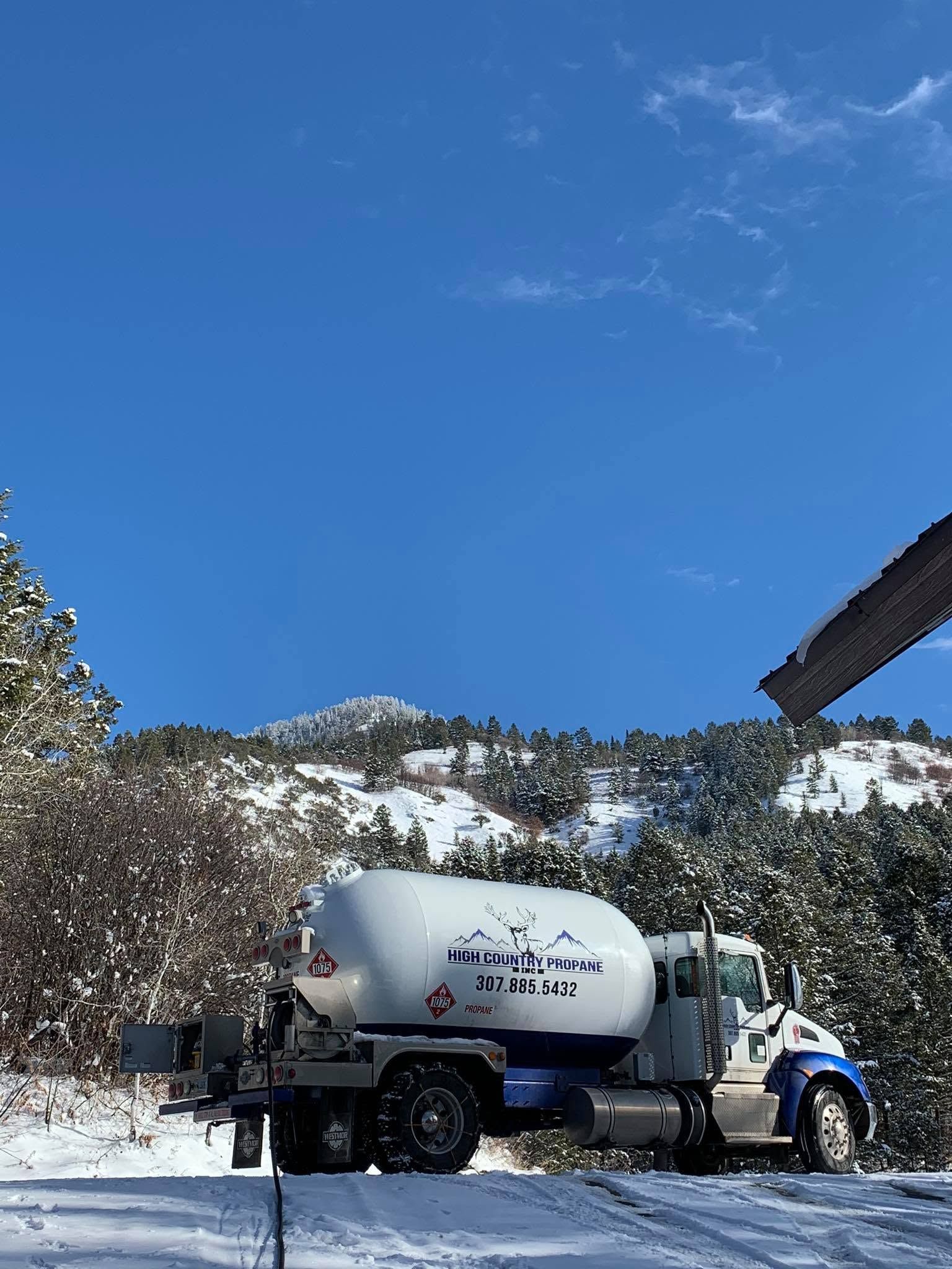 Snow-covered cement mixer truck on a mountain road under a clear blue sky