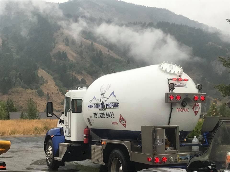 White cement mixer truck on a mountain road with misty forested hills in the background