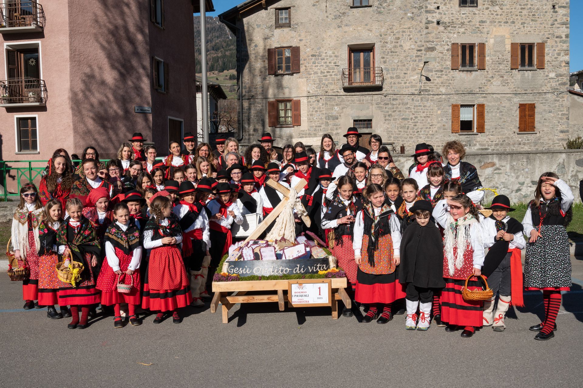 Un folto gruppo di bambini posa per una foto davanti a un edificio.