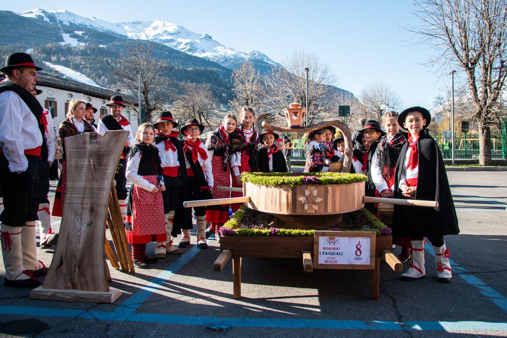 Un gruppo di persone è in piedi attorno a una botte di legno in un parcheggio.