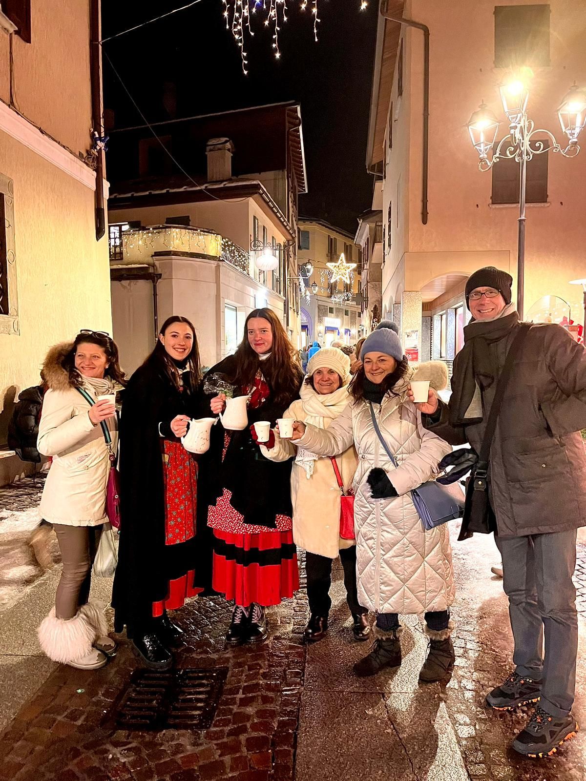 Un gruppo di persone è in piedi su un marciapiede con in mano tazze di caffè.