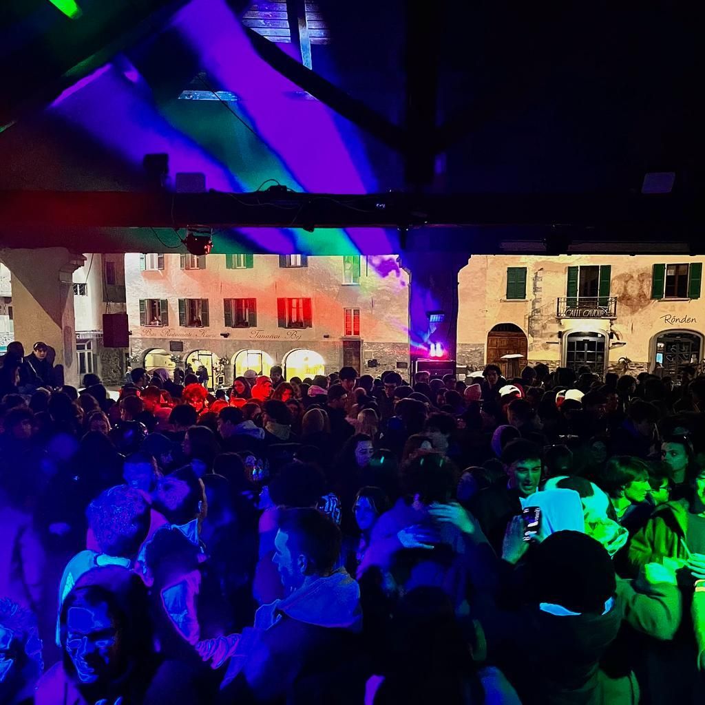 Una folla di persone è riunita in una stanza buia durante una festa.
