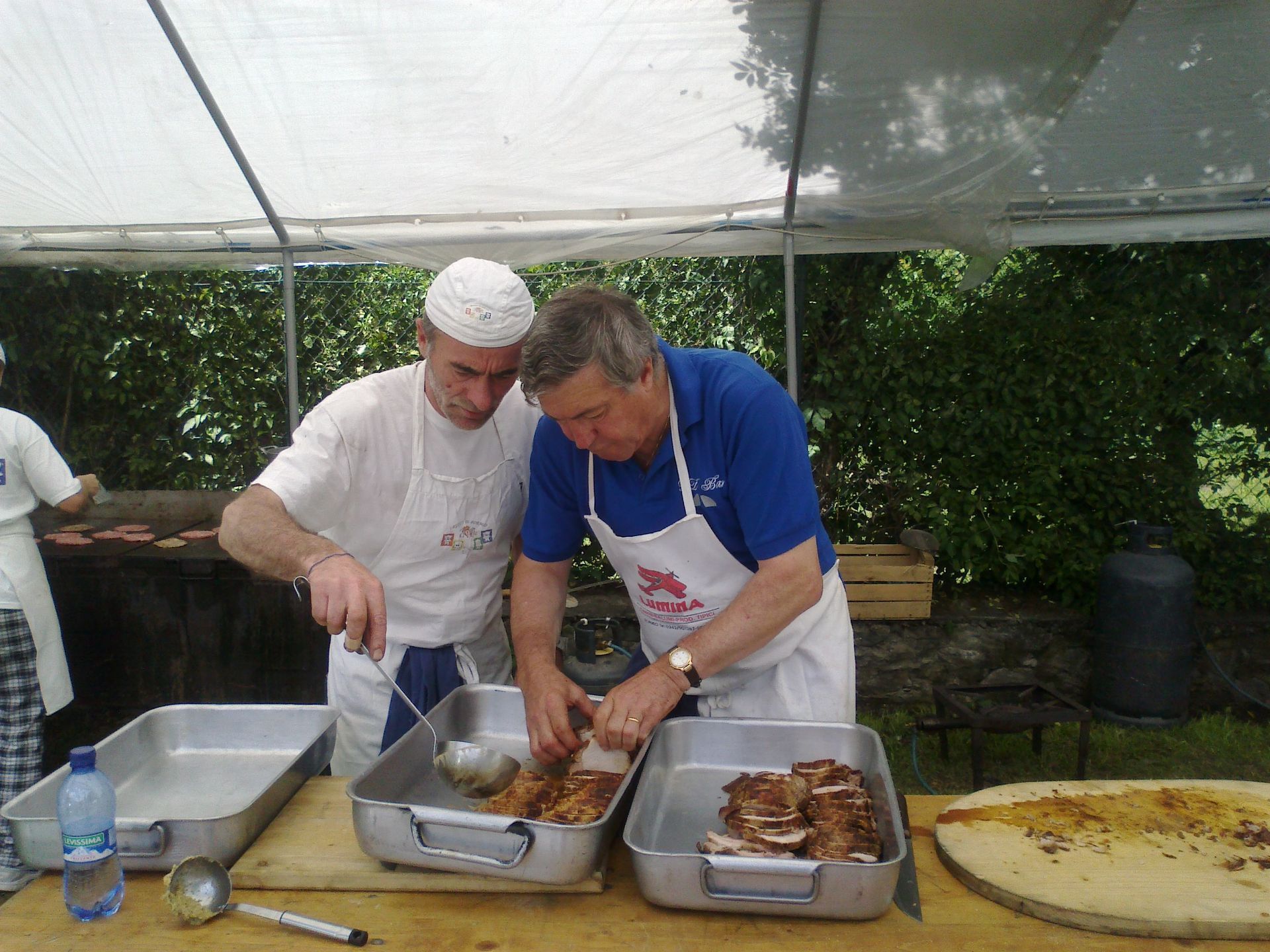 Due uomini in grembiule stanno preparando il cibo su un tavolo
