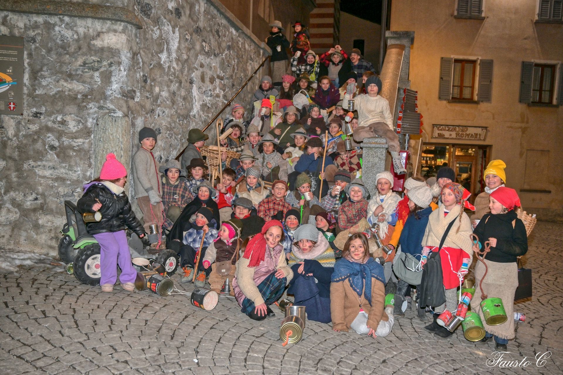 Un gruppo di bambini in costume posa per una foto su una strada acciottolata.