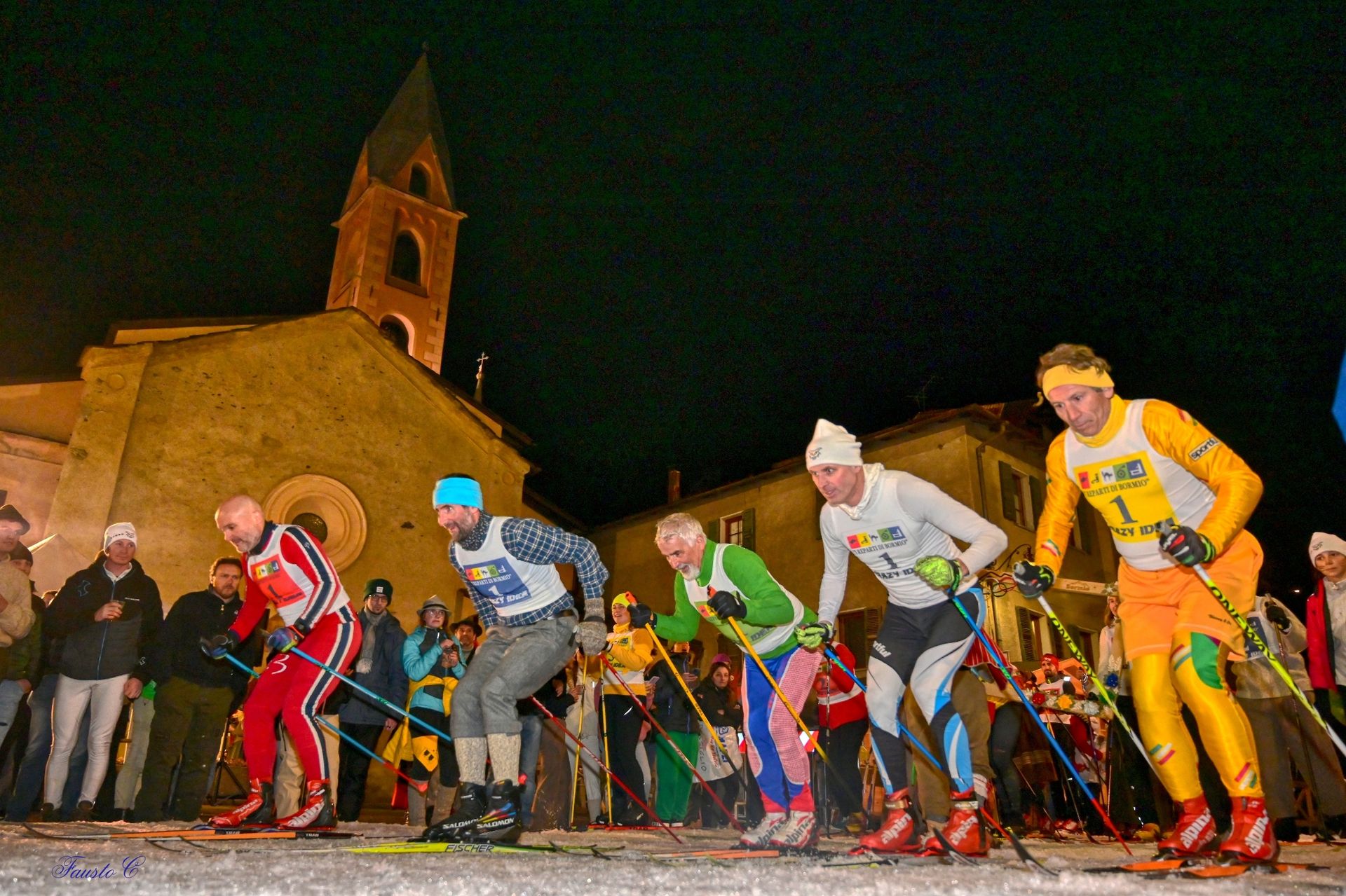 Un gruppo di sciatori è in fila davanti ad una chiesa di notte