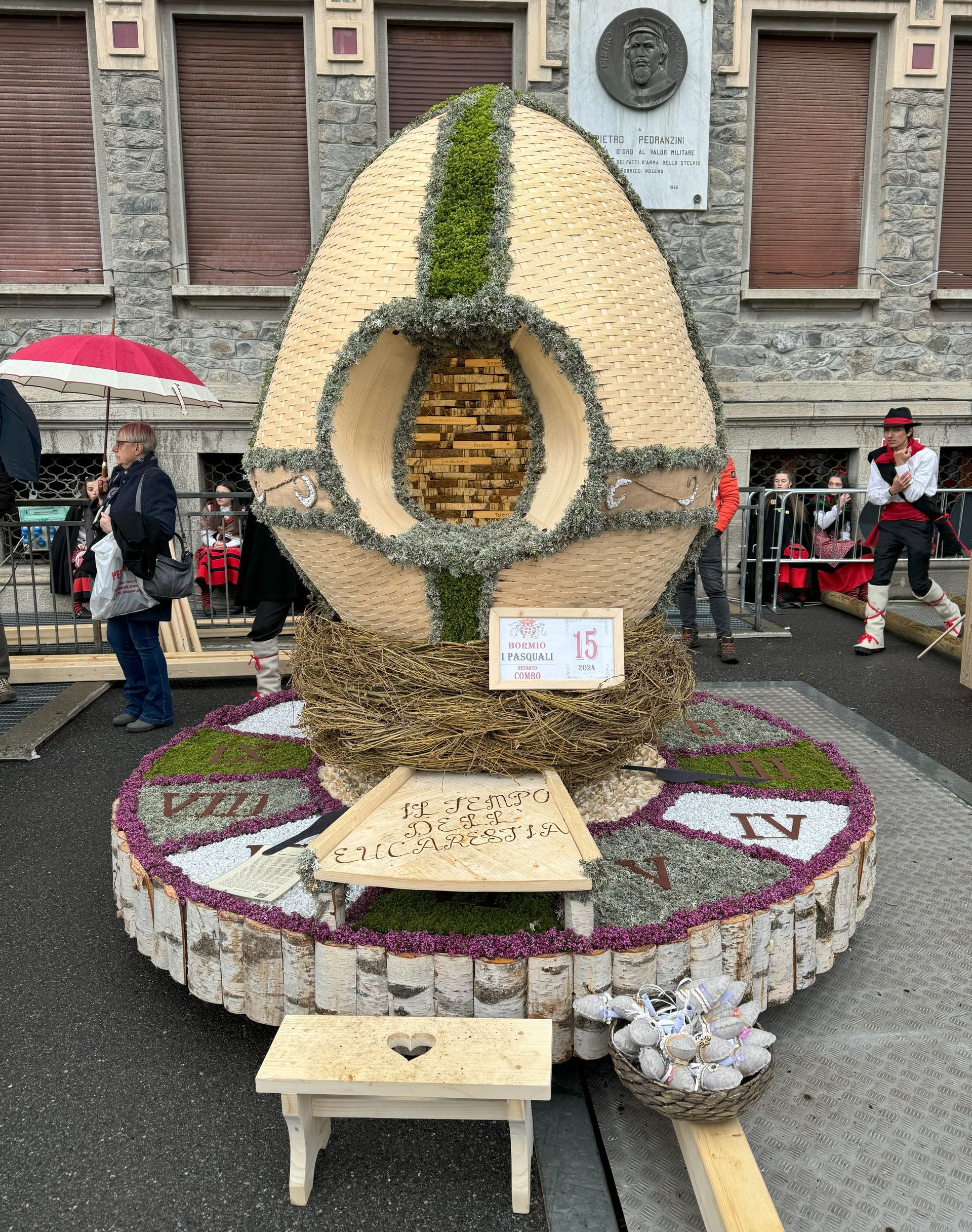 Un grande uovo fatto di fiori è appoggiato su una piattaforma di legno.