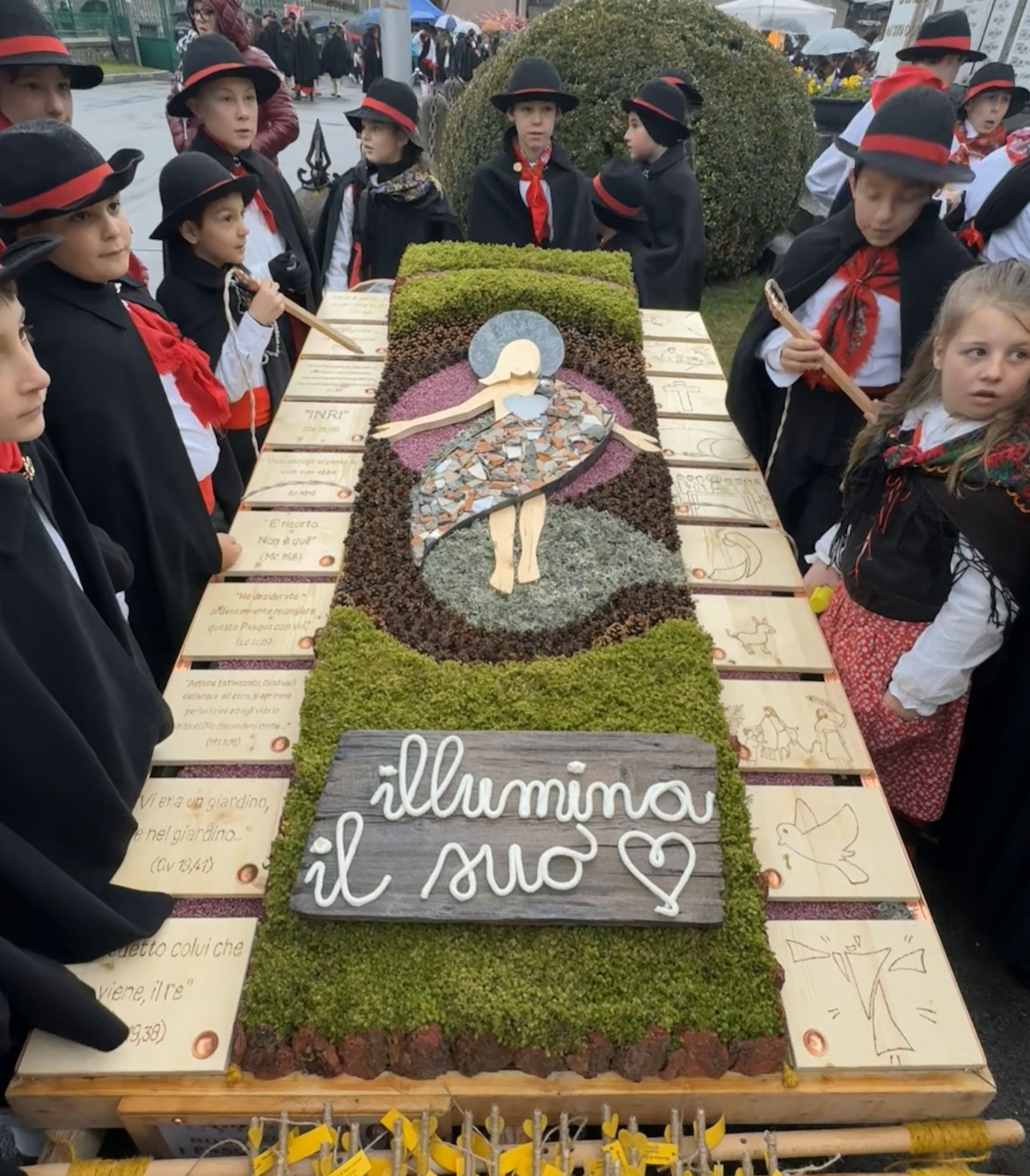 Un gruppo di bambini è in piedi attorno ad un tavolo con un cartello che dice illumina il suo