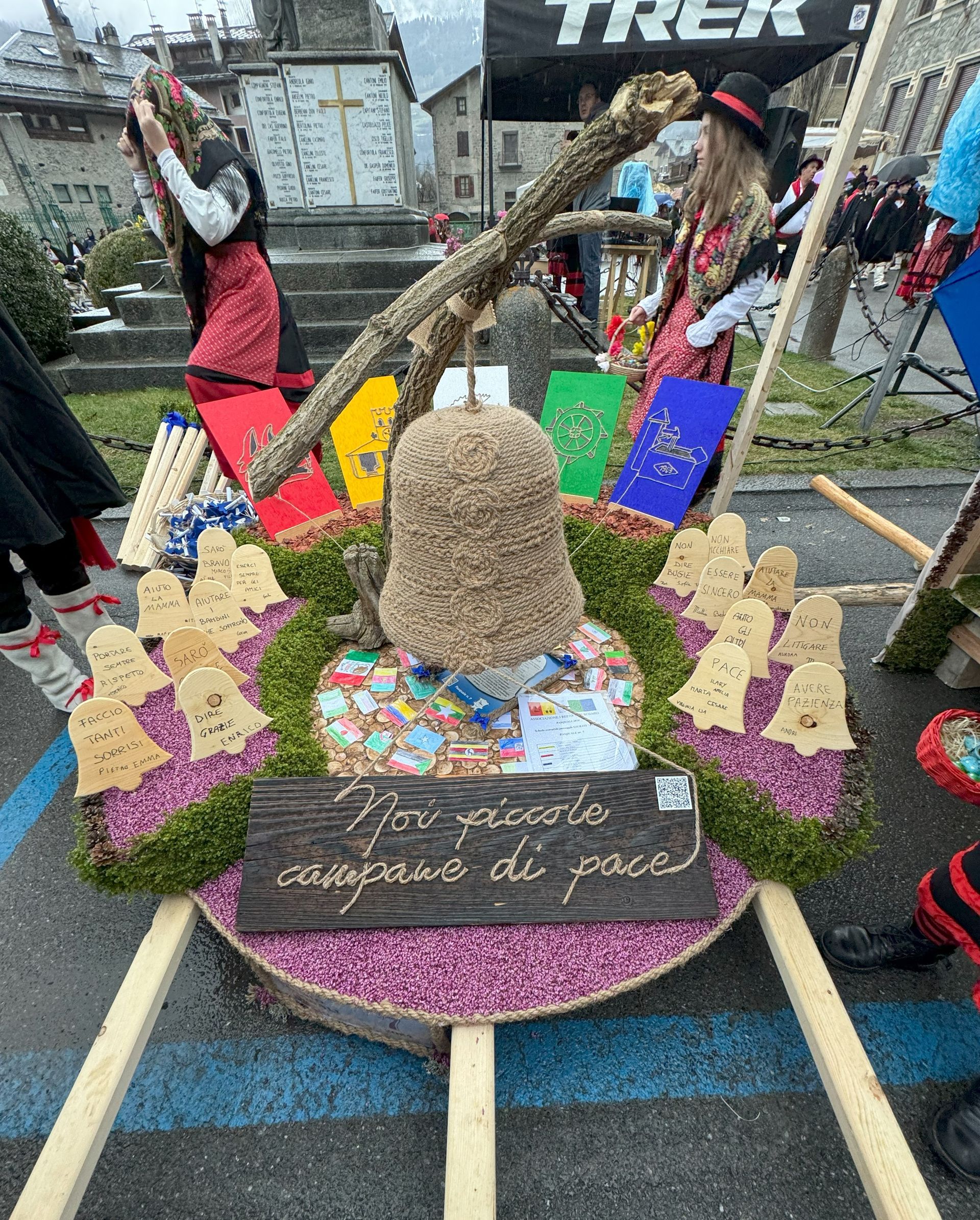 Un gruppo di persone sta attorno ad un'esposizione di fiori e campanelli.