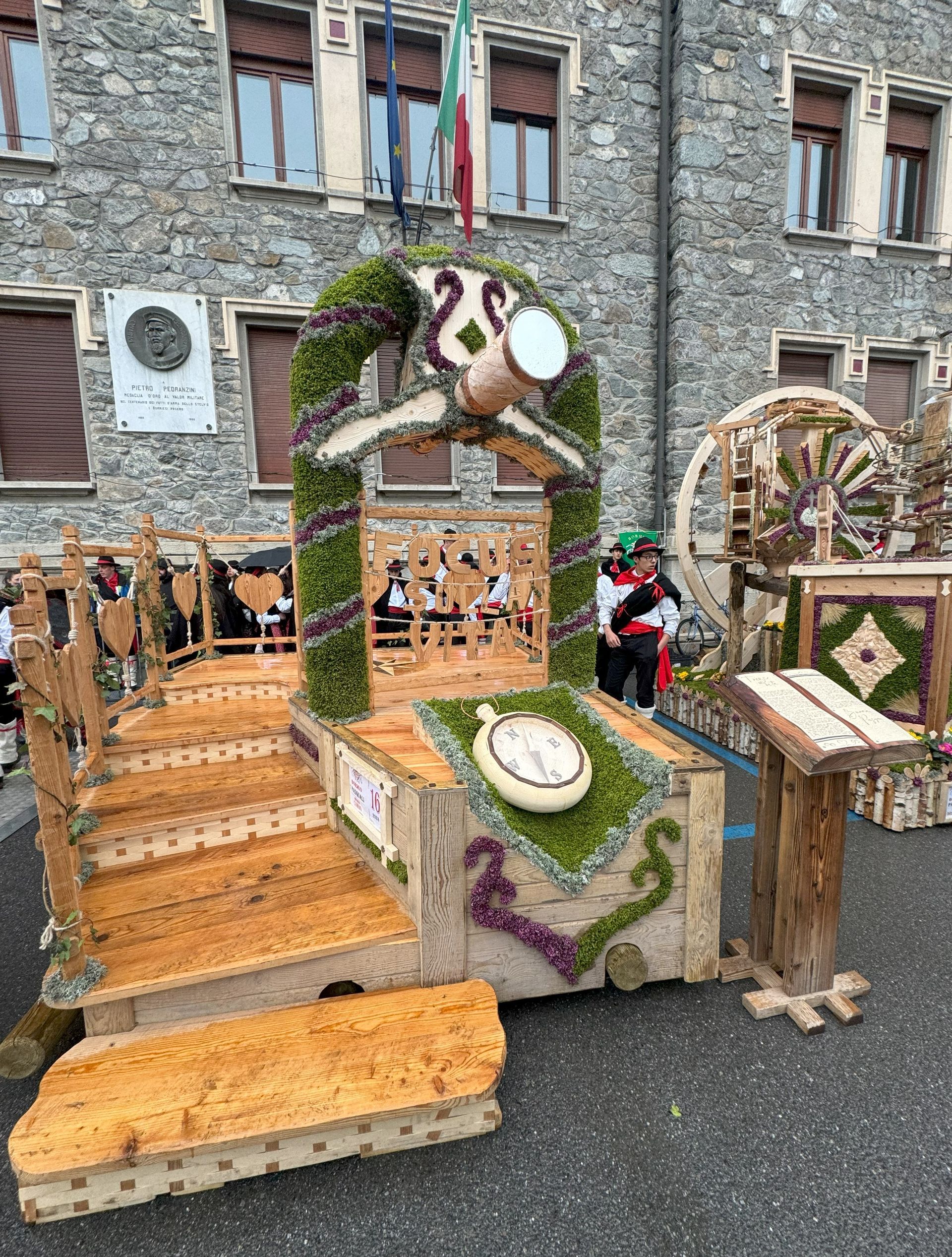 Un carro di legno con sopra un orologio è seduto di fronte a un edificio in pietra.