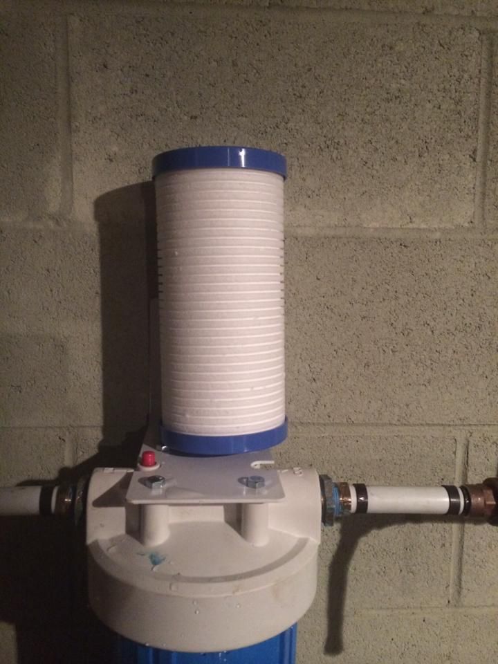 A water filter is attached to a brick wall.