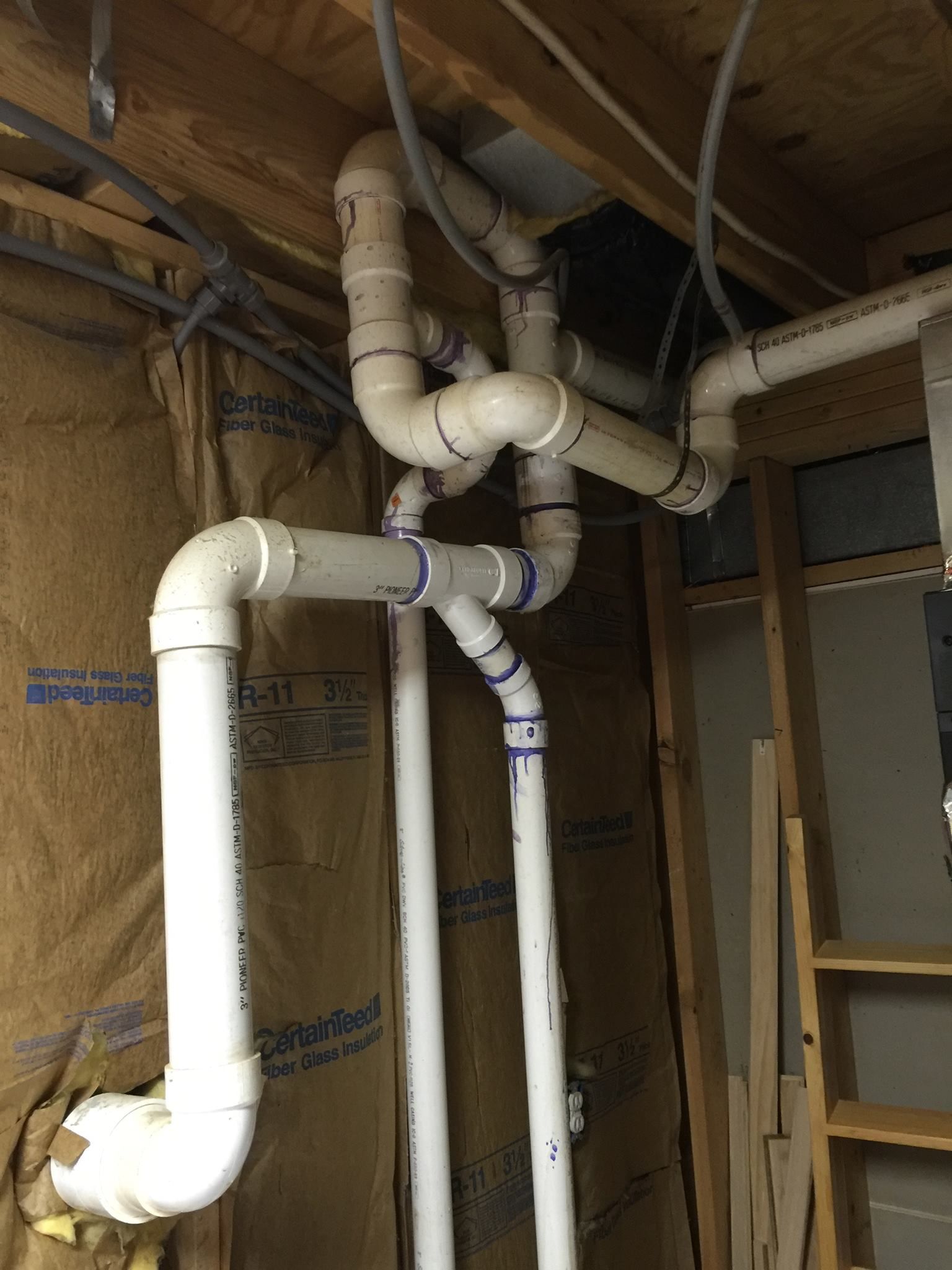 A bunch of white pipes are hanging from the ceiling in a room.