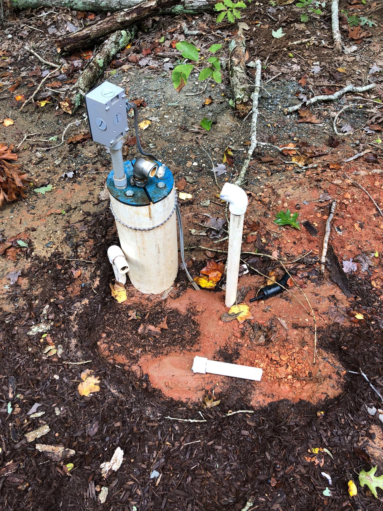 A water pump is sitting in the middle of a dirt field.
