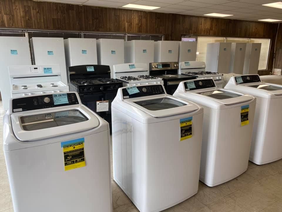 Laundry room with several white top-loading washing machines in a row