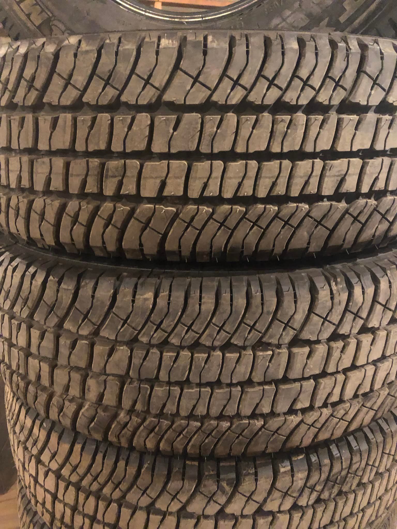 Stacked black all-terrain tires with deep tread patterns, shown close up.