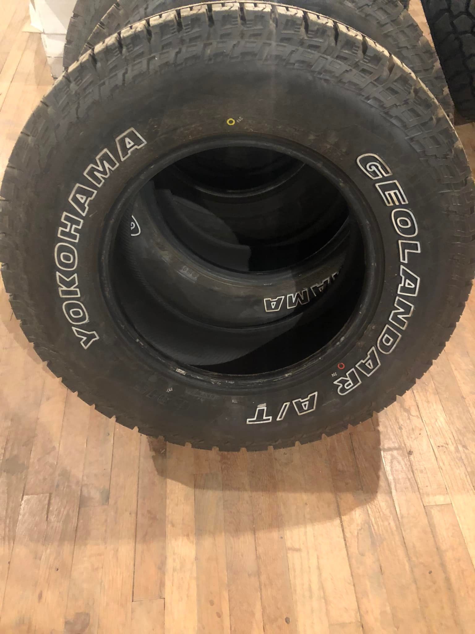 Black KTOMAMA tire with white lettering on a wooden floor; a second tire is visible inside.