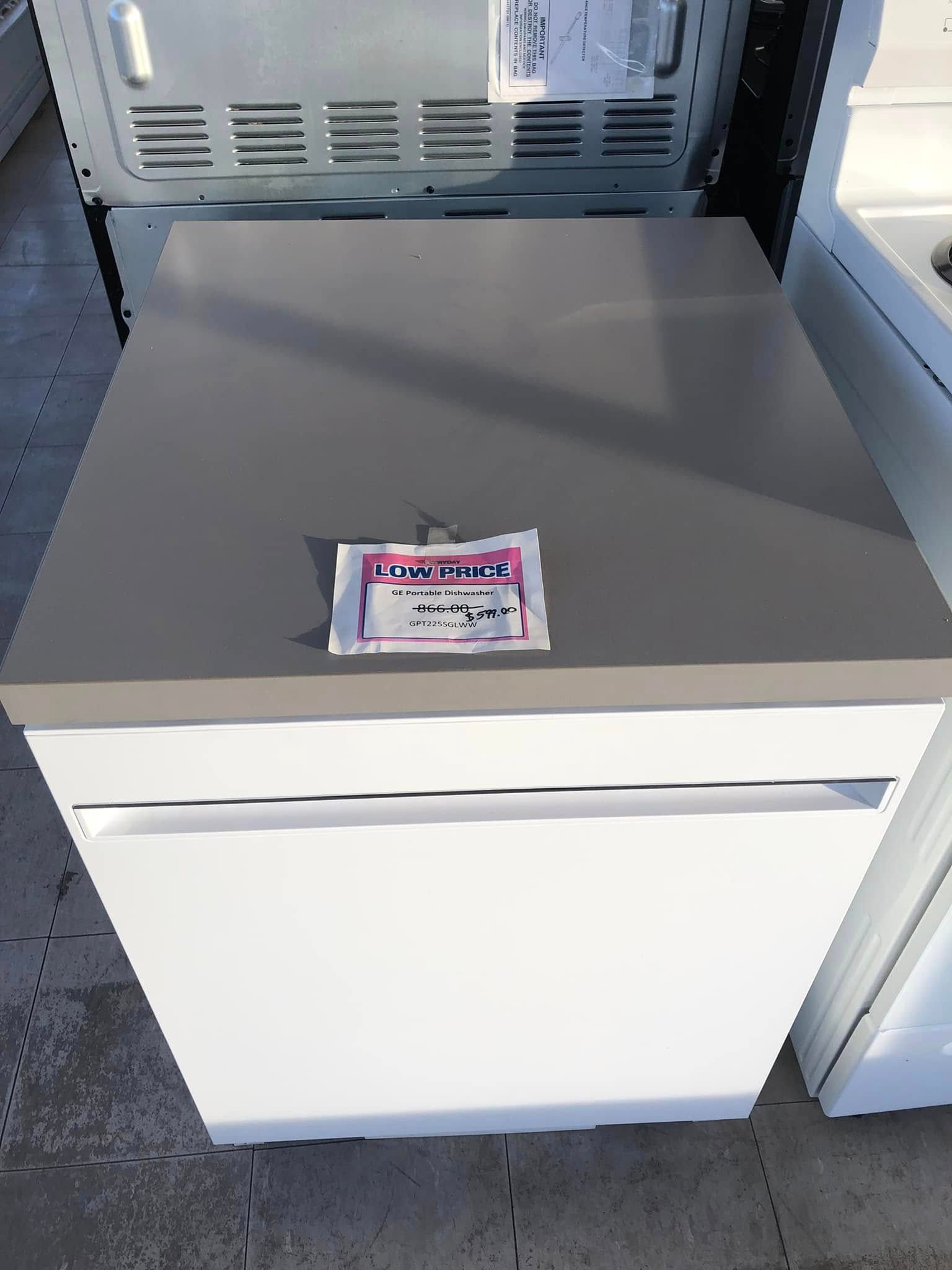 White chest freezer with a gray lid and a small label on top, shown in a store or warehouse aisle