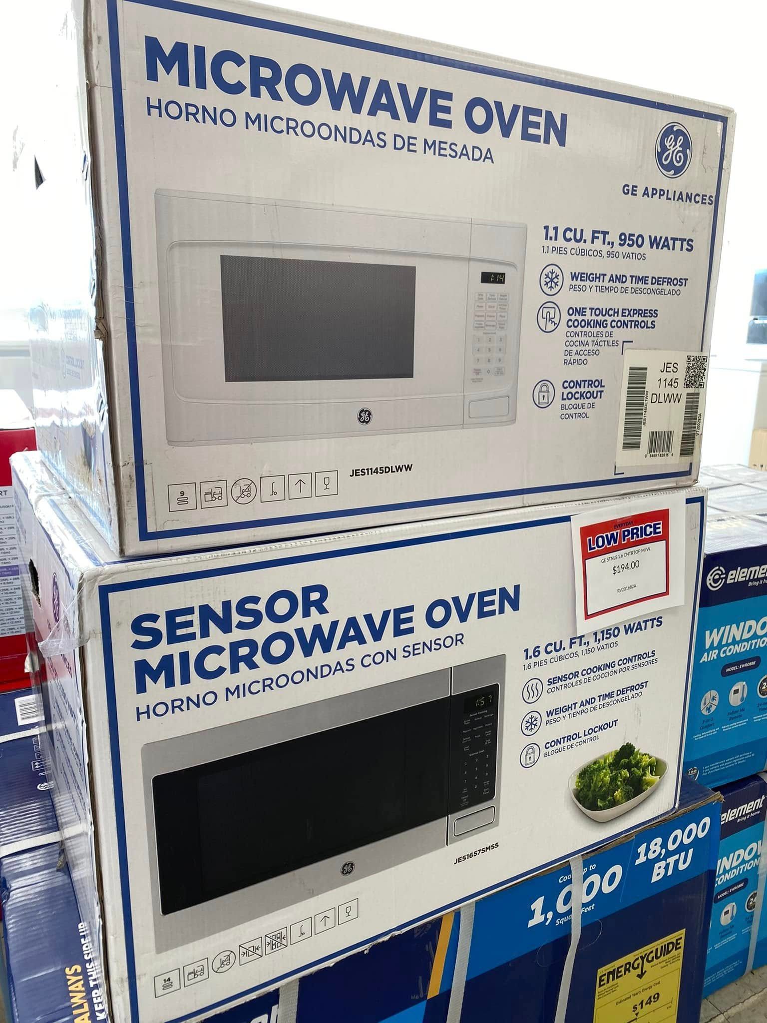 Two microwave ovens on a store shelf, with product labels and blue-and-white packaging.