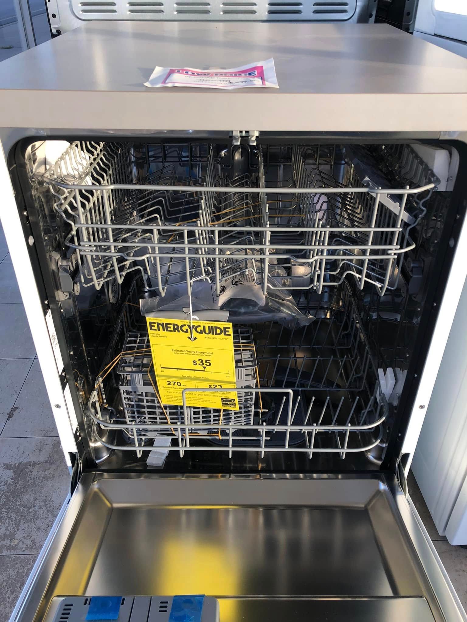 Open dishwasher with top and bottom racks; yellow cleaning notice on the lower rack.