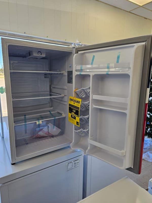Open refrigerator with empty shelves and a yellow tag hanging from the door