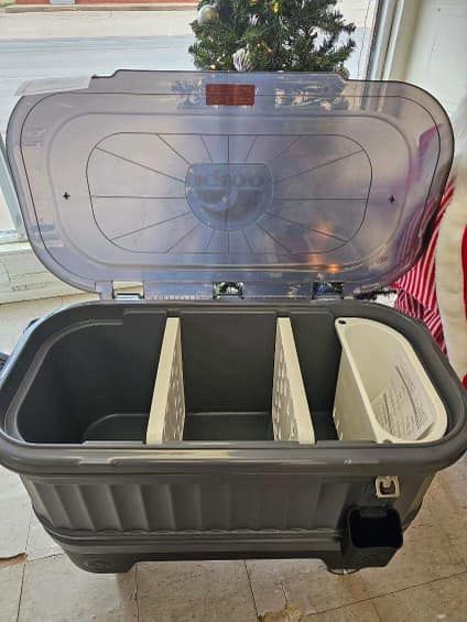 Open cooler with clear lid and white dividers, sitting outdoors on a patio.