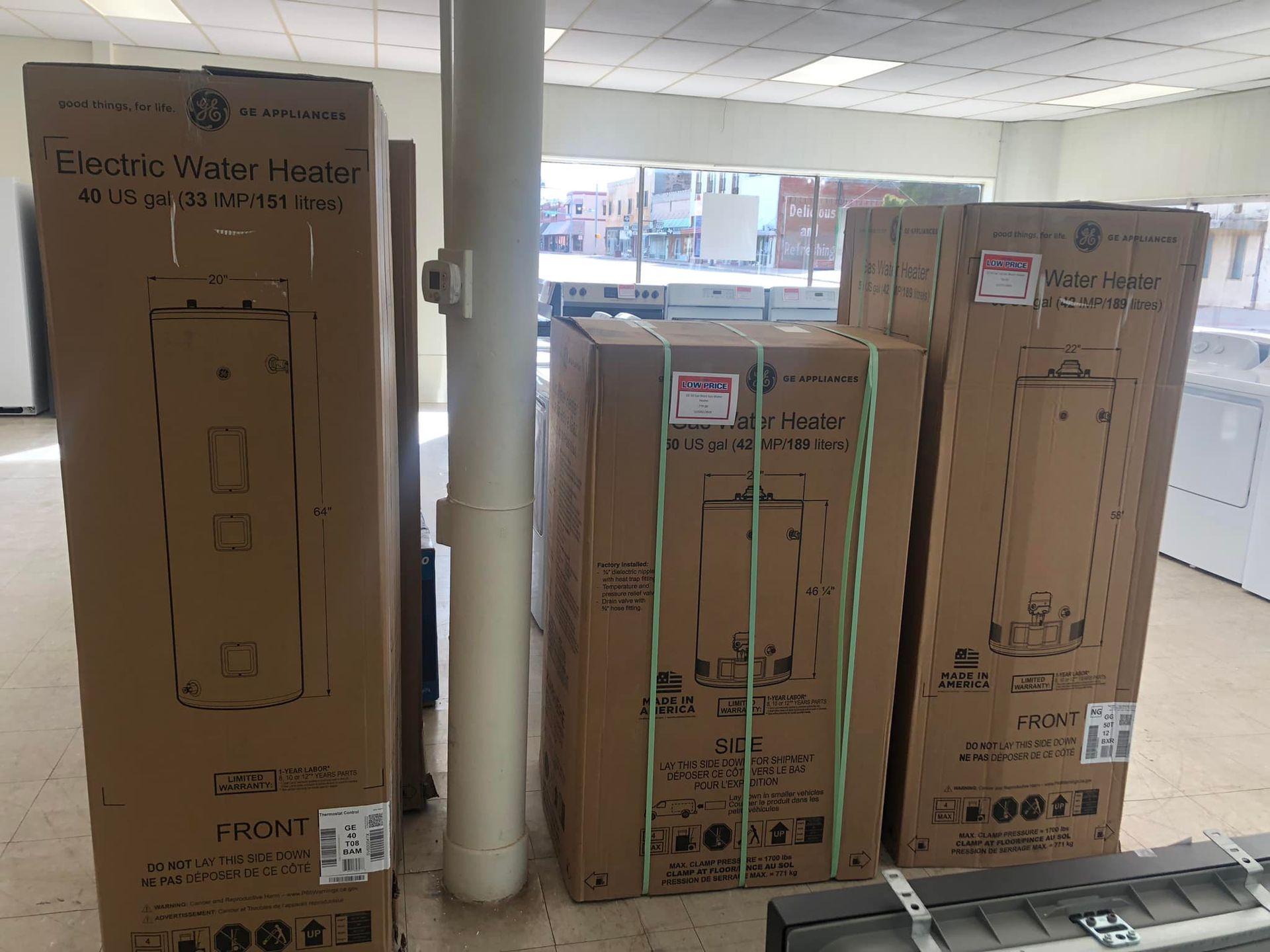 Cardboard boxes stacked in a bright lobby near large windows and a white pillar